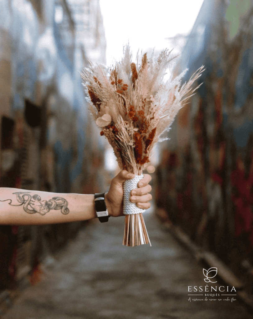 Buquê de flores desidratadas em tons verde, palha e vermelho com folhagem e fita decorativa, ideal para casamento civil.