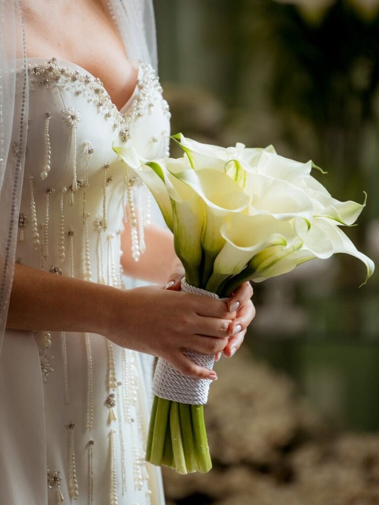 Buquê de Callas Brancas em formato circular sem folhagem e com fita decorativa, ideal para casamento religioso.